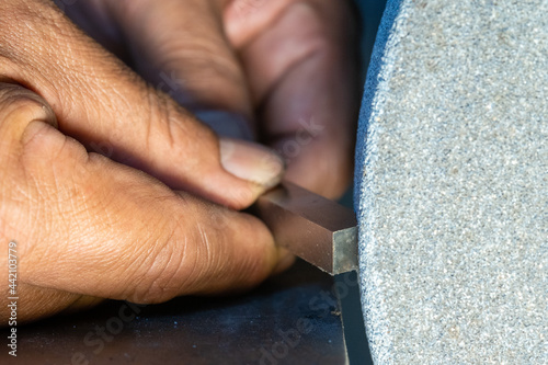 A man grinding a tool bit by using a grinding machine