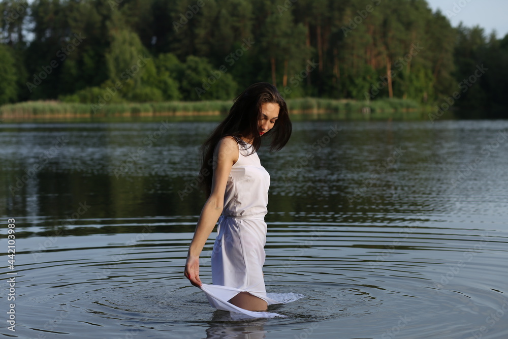 Brunette woman in white dress standing in water Brunette woman in white dress standing in water