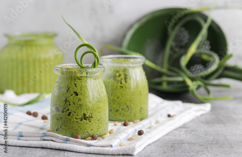 Homemade organic pesto sauce made from fresh arrows of garlic,dill and oil in a glass jar.