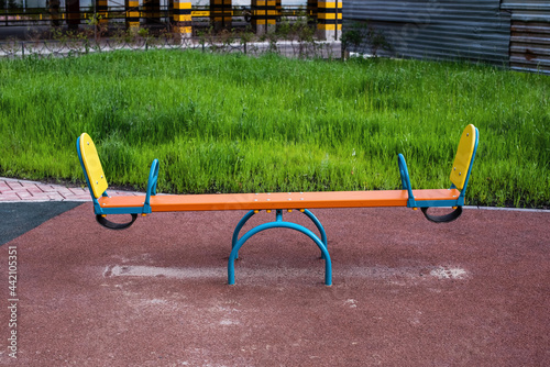 Swing balancer on the playground, green grass, parking and metal fence photo