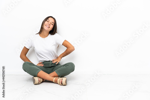 Teenager girl sitting on the floor posing with arms at hip and smiling
