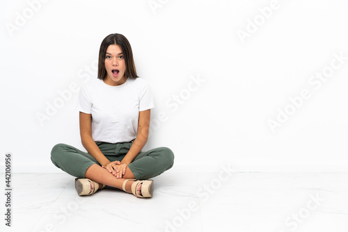 Teenager girl sitting on the floor with surprise facial expression
