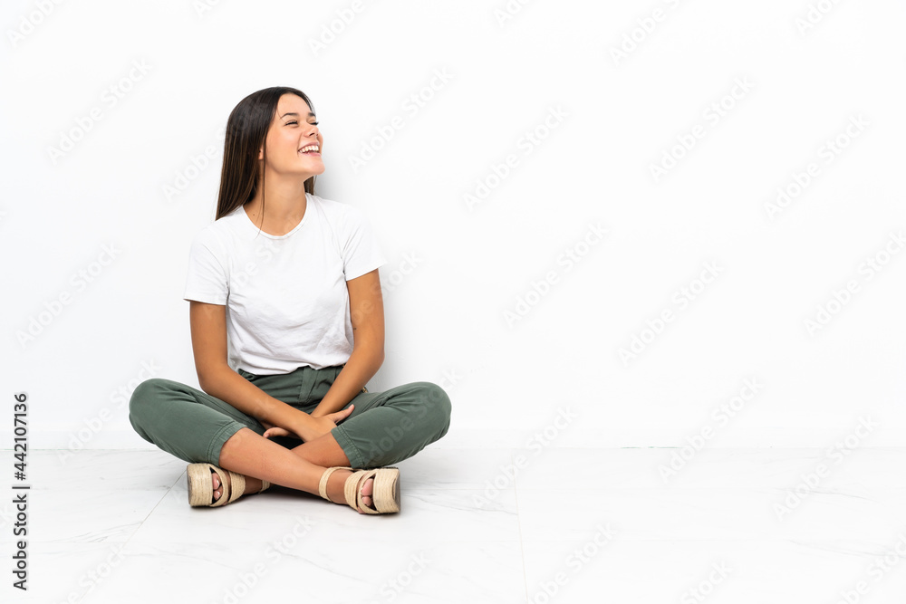 Teenager girl sitting on the floor laughing in lateral position Teenager girl sitting on the floor laughing in lateral position