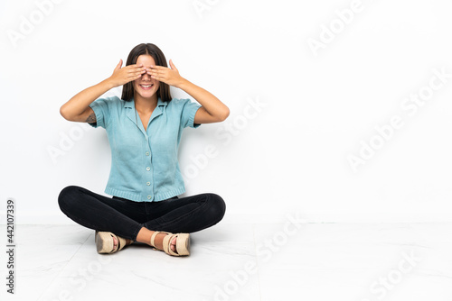 Teenager girl sitting on the floor covering eyes by hands