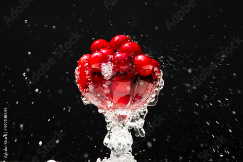 Ripe cherries in a glass. Juicy cherries in a glass with splashing water on a black background.