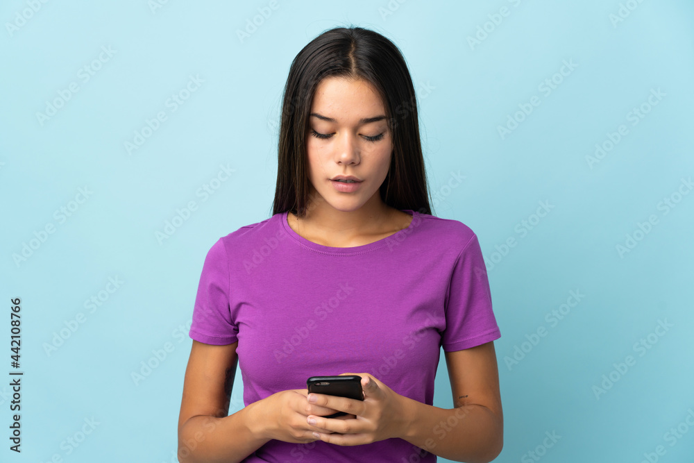 Teenager girl isolated on pink background using mobile phone Teenager girl isolated on pink background using mobile phone