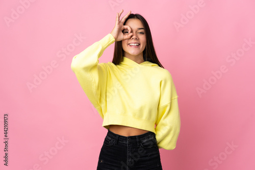 Teenager girl isolated on pink background showing ok sign with fingers