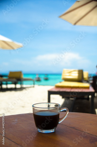 Black coffee on the wooden table, beachside, travel concept , nature light. Thailand