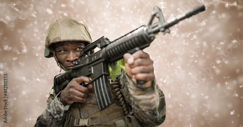 Fotografie Composition of soldier firing gun, against motion blur brown background