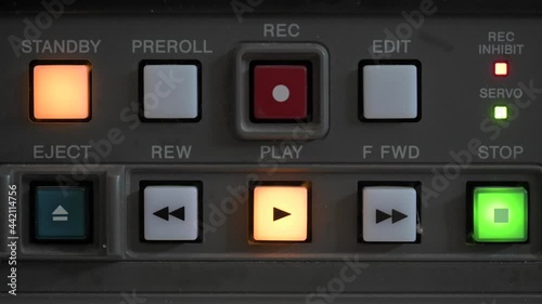 Close up of the control panel of an old broadcasting recorder where we can see the play buttons while a person presses the stop button photo