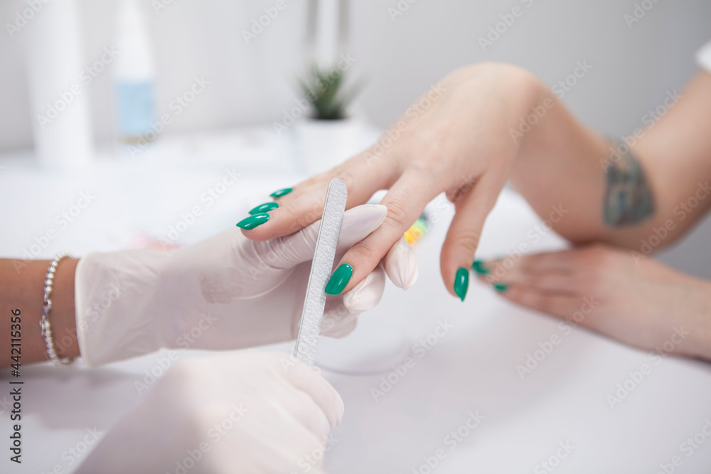 Unrecognizable woman having her nails filed by professional manicurist