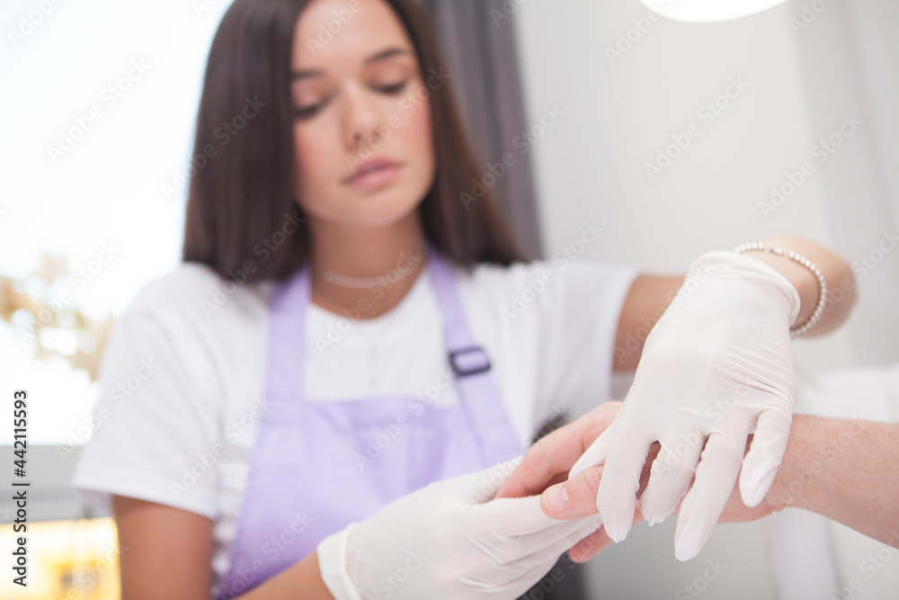 Professional manicurist massaging hand of male client after manicure