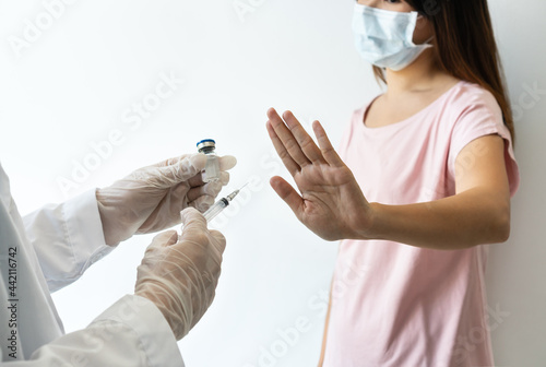 Asian woman wearing surgical mask refuse nurse injection or vaccination. Rejection of the vaccine, insecurity and fear concept. photo
