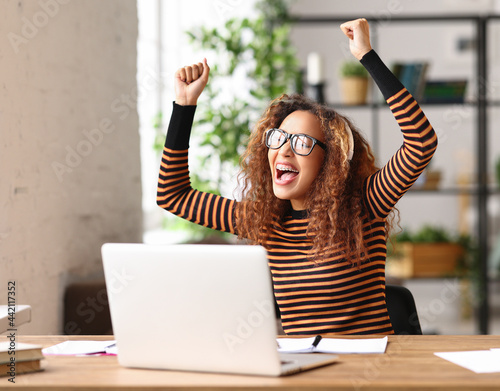 Overjoyed african american female celebrating success while working remotely or studying online from home