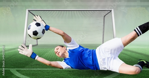 Composition of female goalkeeper catching ball at football stadium photo