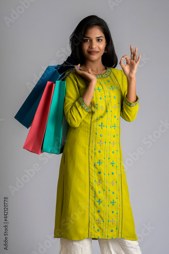 Beautiful young girl holding and posing with shopping bags on a grey background