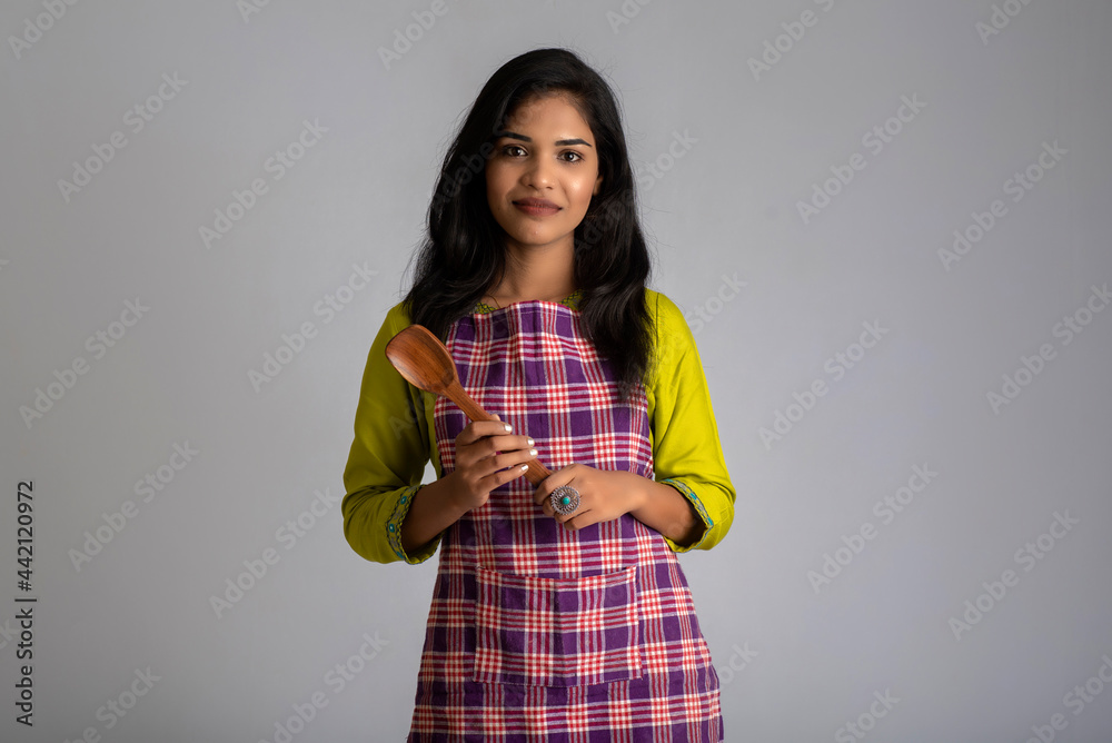 Young girl holding and posing with kitchen utensils spatula on a grey background Young girl holding and posing with kitchen utensils spatula on a grey background