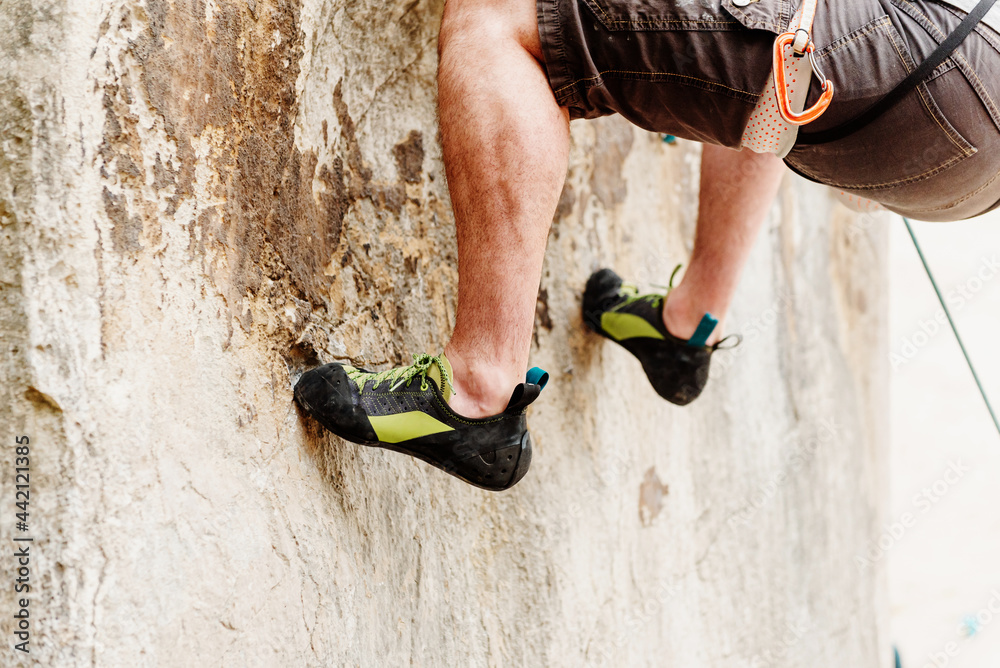 legs and feet of irrecoverable climber holding on to the rock while climbing a mountain
