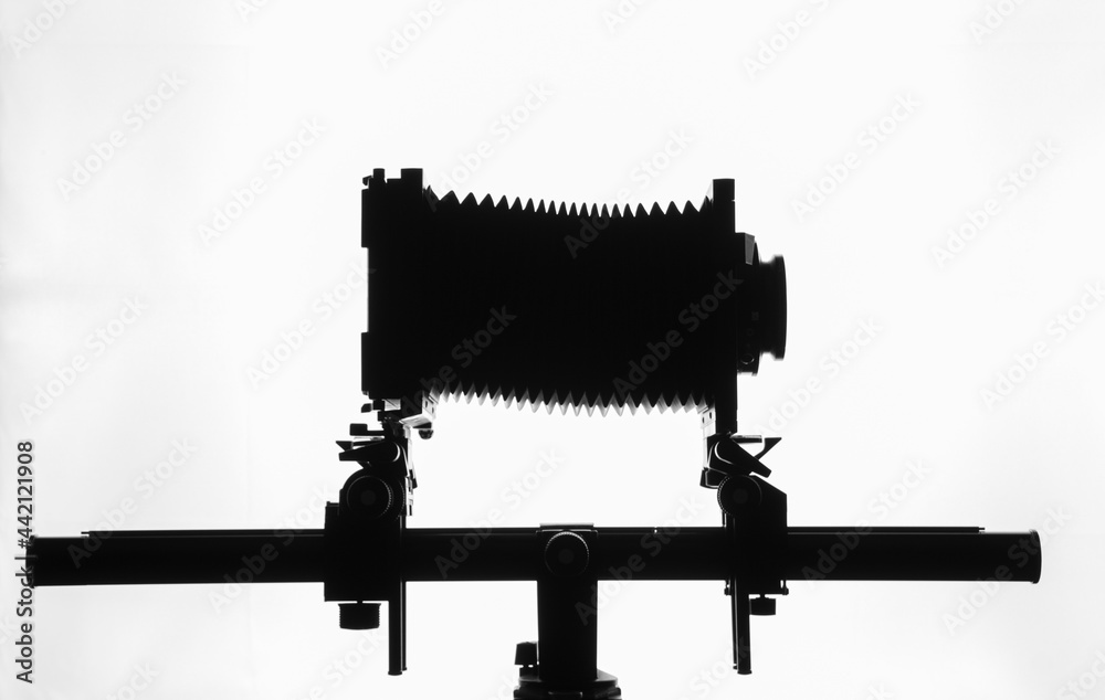 Silhouette of old bellows camera on tripod, horizontal white background, with copy space Silhouette of old bellows camera on tripod, horizontal white background, with copy space