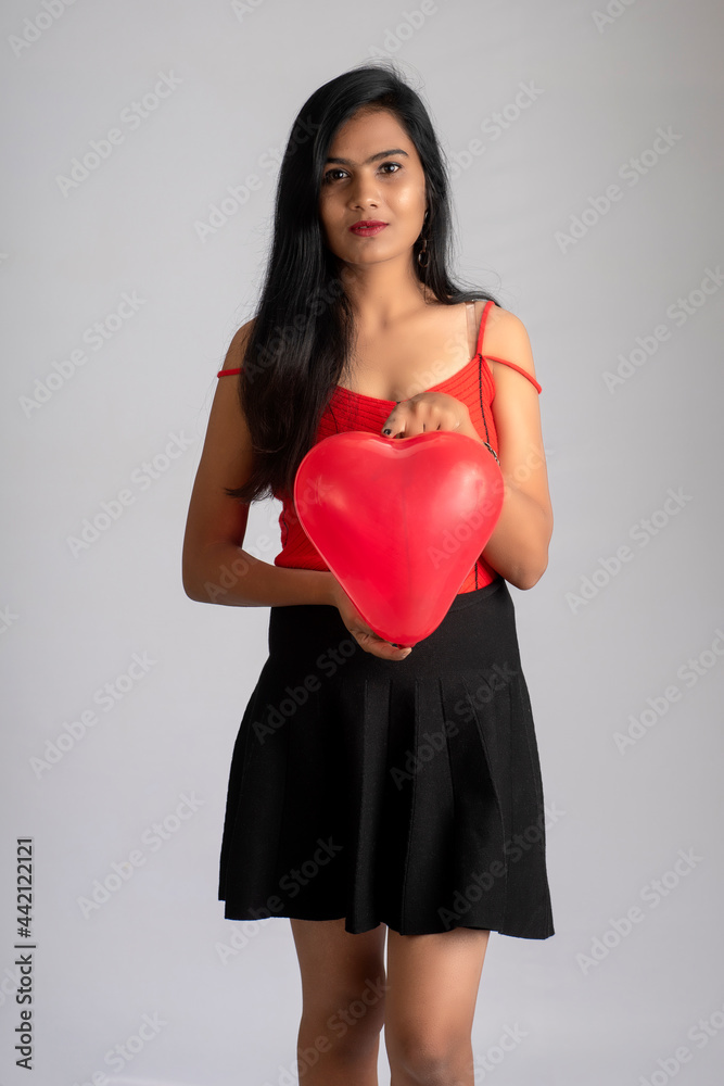 Cheerful cute girl in fancy red and black outfit posing with heart shape balloon. Cheerful cute girl in fancy red and black outfit posing with heart shape balloon.
