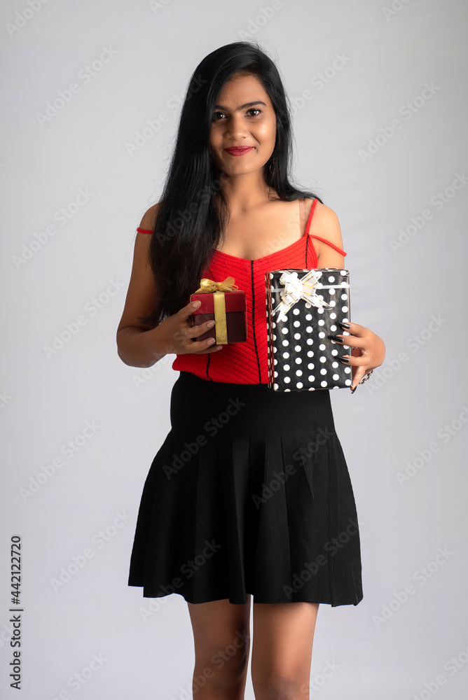 Portrait of a pretty girl holding and posing with gift box on grey background Portrait of a pretty girl holding and posing with gift box on grey background