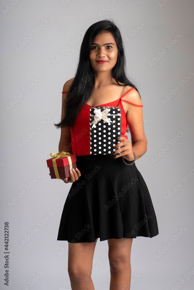 Portrait of a pretty girl holding and posing with gift box on grey background Portrait of a pretty girl holding and posing with gift box on grey background