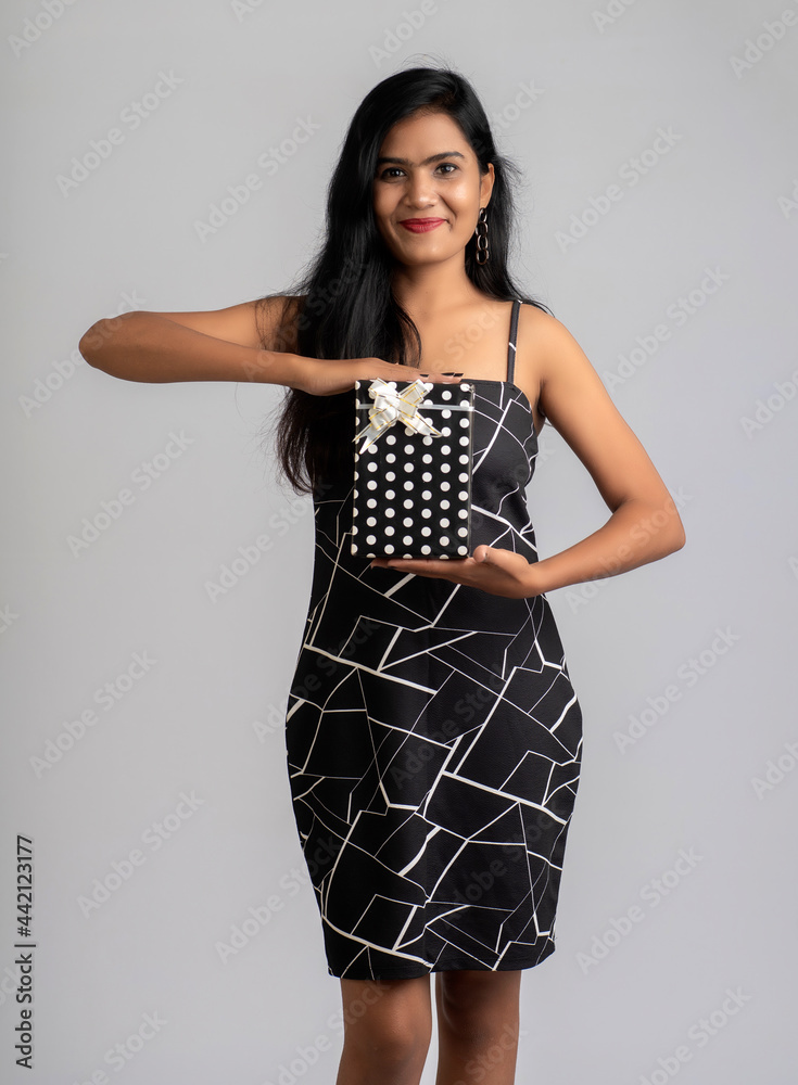 Portrait of a pretty young girl posing with gift box on grey background. Portrait of a pretty young girl posing with gift box on grey background.
