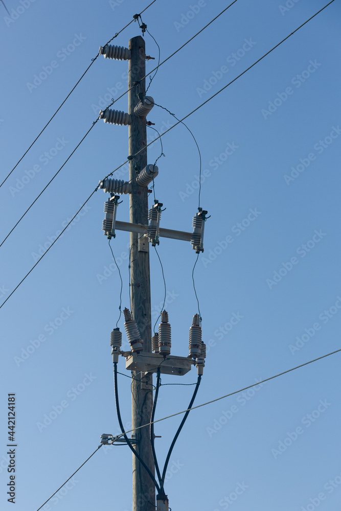 Powerlines and insulators at a pole in front of a blue sky Powerlines and insulators at a pole in front of a blue sky