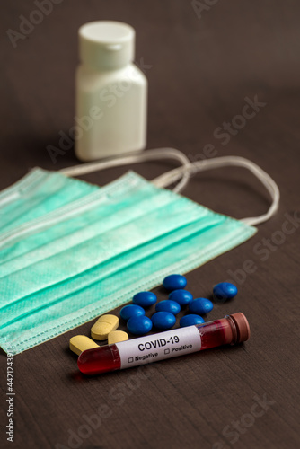 Tube containing a blood sample for testing to the presence of coronavirus / COVID-19 with Mask and medicine tablet.