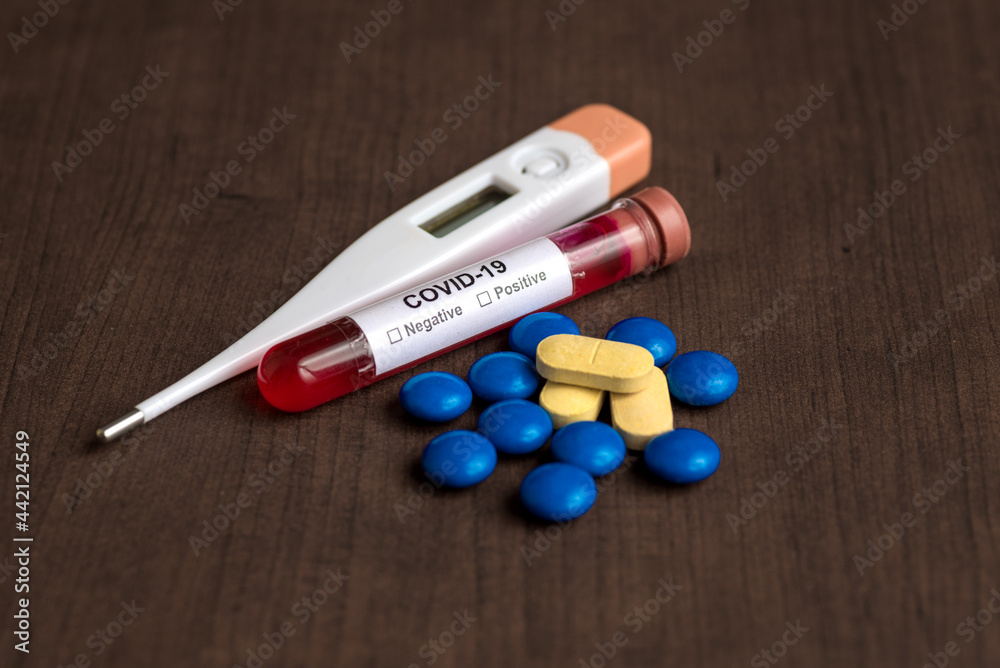 Medicine tablet and Thermometer with Test tube containing a blood sample for testing to the presence of coronavirus / COVID-19
