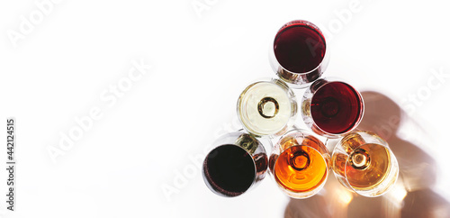 Red, rose and white wine in glasses on white background, top view. Wine bar, shop, winery, wine tasting concept. Hard light and harsh shadows