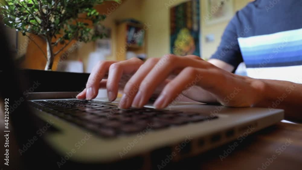 Vue rapprochée d’un étudiant travaillant sur son ordinateur portable. Male student hands typing on laptop at desk, close up view.