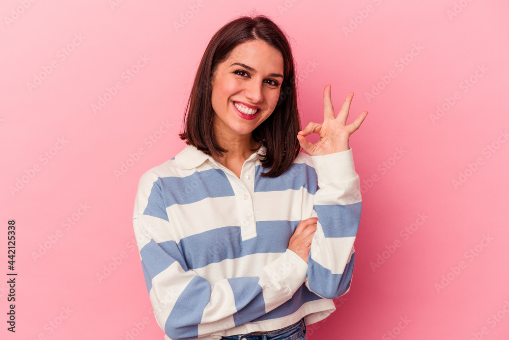 Young caucasian woman isolated on pink background winks an eye and holds an okay gesture with hand. Young caucasian woman isolated on pink background winks an eye and holds an okay gesture with hand.