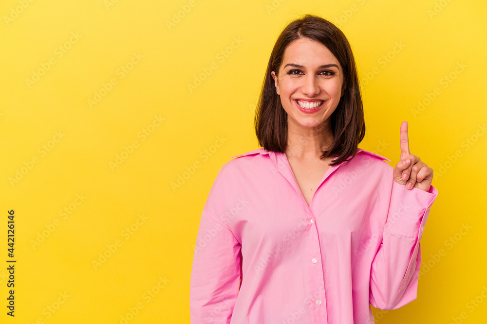 Young caucasian woman isolated on yellow background showing number one with finger. Young caucasian woman isolated on yellow background showing number one with finger.