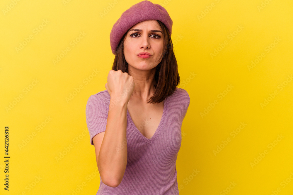 Young caucasian woman isolated on yellow background showing fist to camera, aggressive facial expression. Young caucasian woman isolated on yellow background showing fist to camera, aggressive facial expression.
