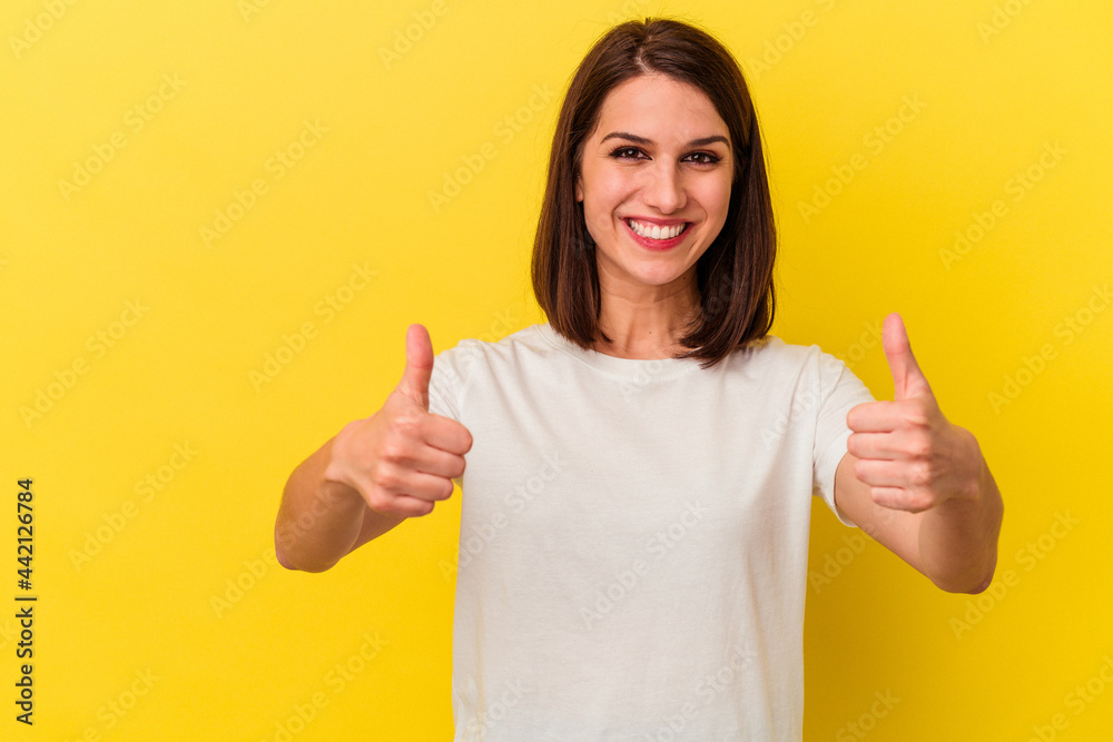 Young caucasian woman isolated on yellow background smiling and raising thumb up Young caucasian woman isolated on yellow background smiling and raising thumb up