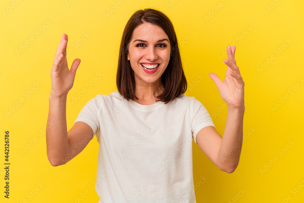 Young caucasian woman isolated on yellow background receiving a pleasant surprise, excited and raising hands. Young caucasian woman isolated on yellow background receiving a pleasant surprise, excited and raising hands.