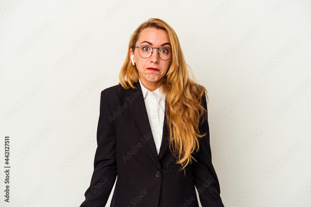 Caucasian business woman wearing a wireless headphones isolated on white background shrugs shoulders and open eyes confused. Caucasian business woman wearing a wireless headphones isolated on white background shrugs shoulders and open eyes confused.