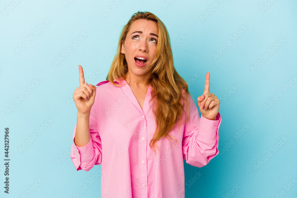Caucasian woman isolated on blue background pointing upside with opened mouth. Caucasian woman isolated on blue background pointing upside with opened mouth.