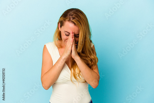 Caucasian woman isolated on blue background praying, showing devotion, religious person looking for divine inspiration.