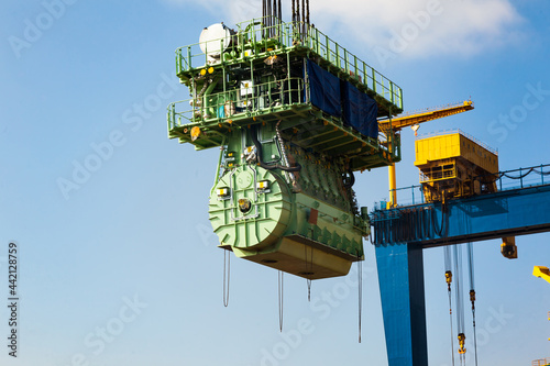 Billede på lærred Transportation of a large marine engine by a port crane using steel cables
