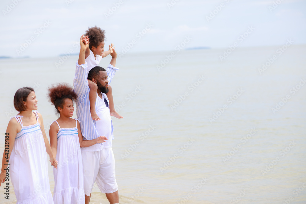 Happy African american family holding hands and walking together on the beach during holiday.