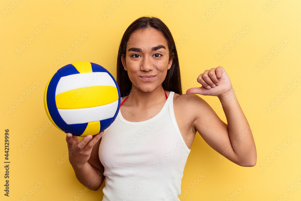 Young mixed race woman playing volleyball on the beach isolated on yellow background feels proud and self confident, example to follow.