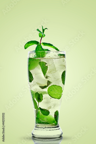 A glass with a mojito on a green background. Cold ice drink.