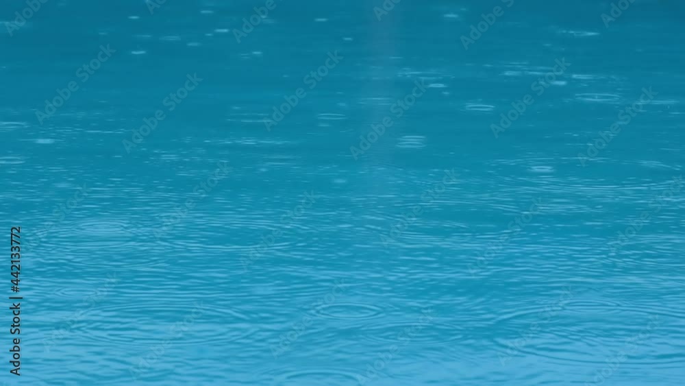 Rain splashes hit the blu water, heavy rain, close-up Rain splashes hit the blu water, heavy rain, close-up