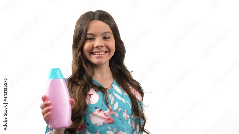 happy teen girl turning showing her long curly hair presenting shampoo show thumb up, daily habits. happy teen girl turning showing her long curly hair presenting shampoo show thumb up, daily habits.