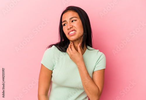 Young Venezuelan woman isolated on pink background touching back of head, thinking and making a choice.