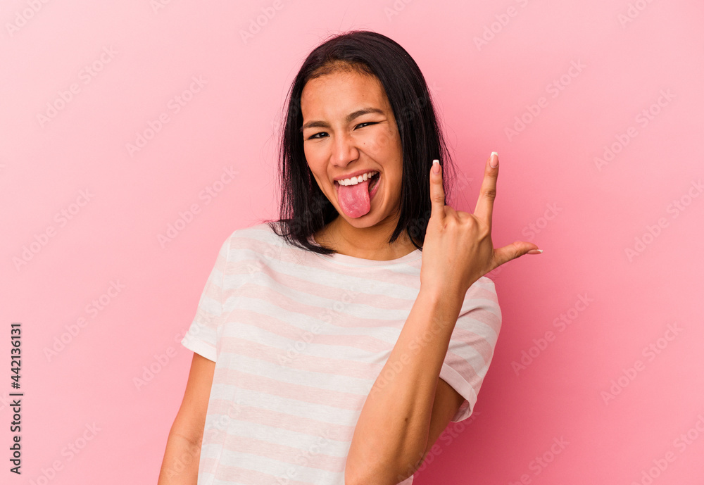 Young Venezuelan woman isolated on pink background showing rock gesture with fingers Young Venezuelan woman isolated on pink background showing rock gesture with fingers