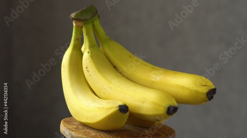 A bunch of yellow bananas. Sweet fruit. Wooden base. Dark background. Close-up.