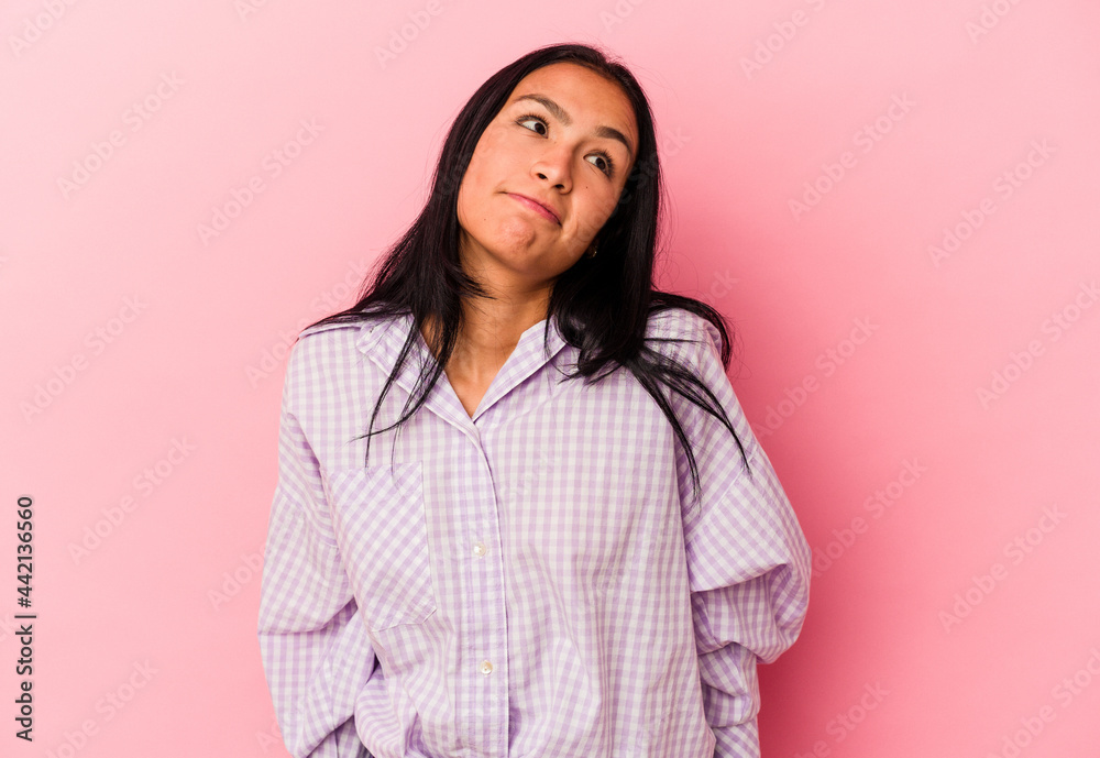 Young Venezuelan woman isolated on pink background shrugs shoulders and open eyes confused. Young Venezuelan woman isolated on pink background shrugs shoulders and open eyes confused.